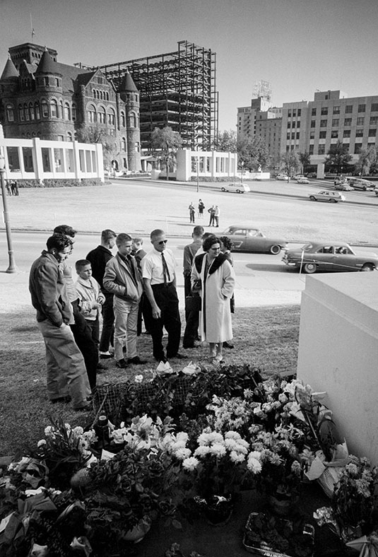 Photograph of visitors gathering at a memorial for President John F. Kennedy in Dealey Plaza, near the site where he was fatally shot in Dallas, Texas.